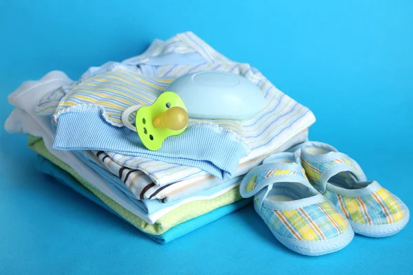 Pile of baby clothes on blue background — Stock Photo, Image