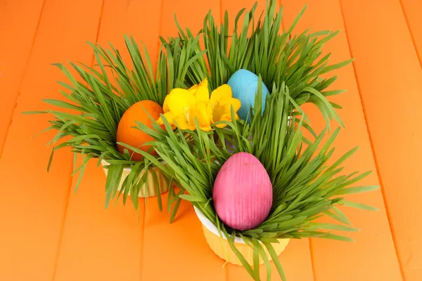 Paskalya yumurtaları kase çim üzerinde turuncu ahşap masa ile yakın çekim — Stok fotoğraf