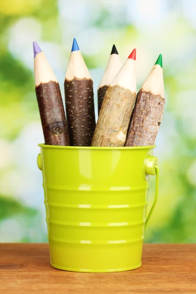 Lápices de madera coloridos en cubo sobre mesa de madera sobre fondo brillante —  Fotos de Stock