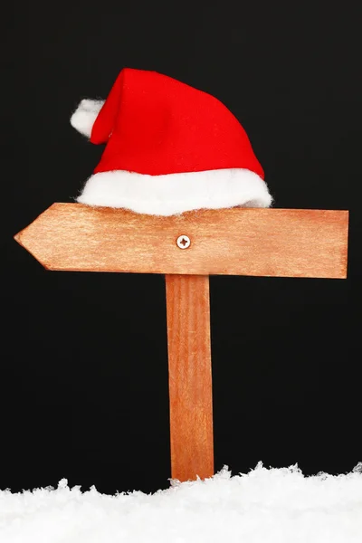 Wooden road sign with Santa hat black background — Stock Photo, Image