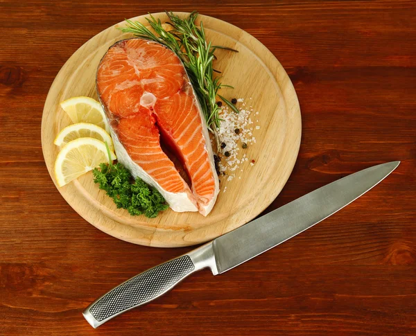 Fresh salmon steak on cutting board, on wooden background — Stock Photo, Image