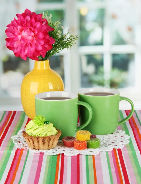 Tazas de té con pastel, dulces y flores en la mesa en la habitación —  Fotos de Stock