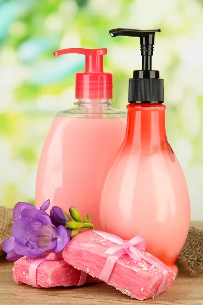 Liquid and hand-made soaps on wooden table, on green background — Stock Photo, Image