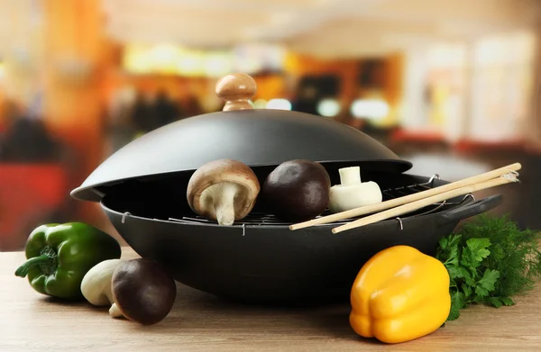 Padella wok nero e verdure sul tavolo di legno della cucina, primo piano — Foto Stock