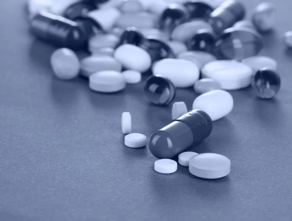 Asortyment pigułki, tabletki i kapsułki w świetle szary — Zdjęcie stockowe
