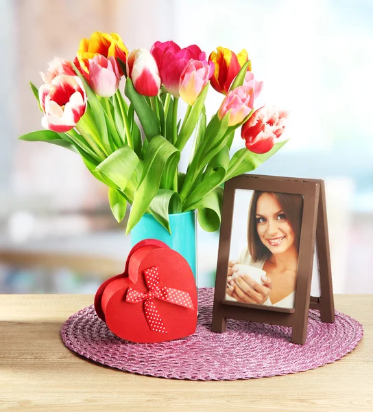 Krásné tulipány v kbelíku s dárky na stole v pokoji — Stock fotografie