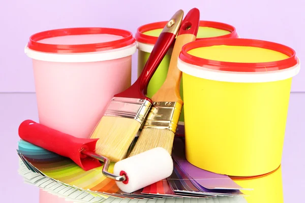 Set pour peinture : pots de peinture, pinceaux, rouleau de peinture, palette de couleurs sur fond lilas — Photo