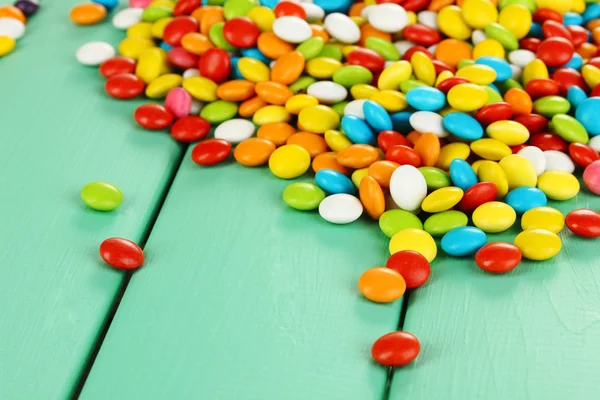 Yeşil ahşap arka plan üzerinde renkli şekerler — Stok fotoğraf