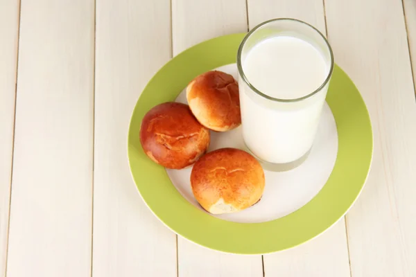 Panecillos y vaso de leche sobre mesa de madera —  Fotos de Stock