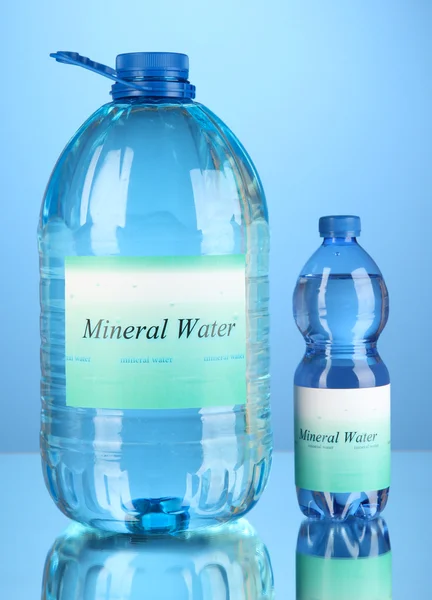 Diferentes botellas de agua con etiqueta sobre fondo azul — Foto de Stock