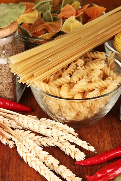 Diversi tipi di pasta, spezie, pomodori su un tavolo di legno — Foto Stock