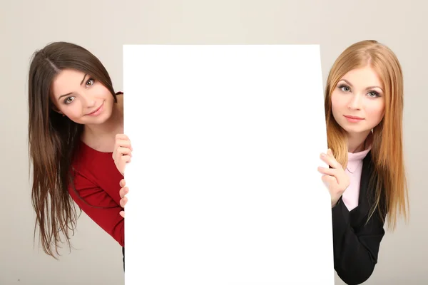 Två affärskvinnor med tomt formulär på grå bakgrund — Stockfoto