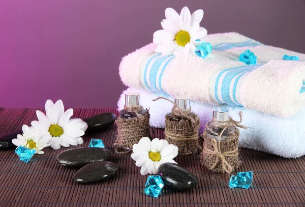 Olej na mat bambusowych na tle różowy ręczniki spa — Zdjęcie stockowe