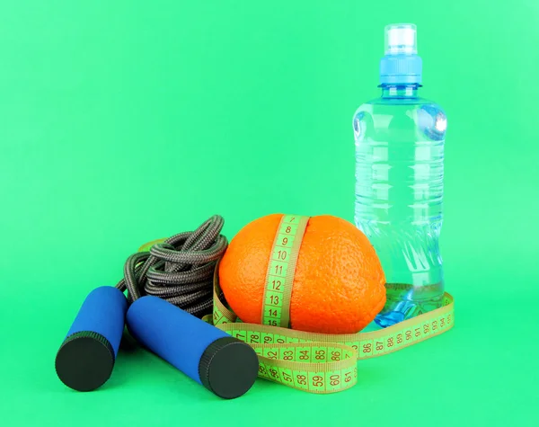 Orange with measuring tape,skipping rope and bottle of water, on color background — Stock Photo, Image