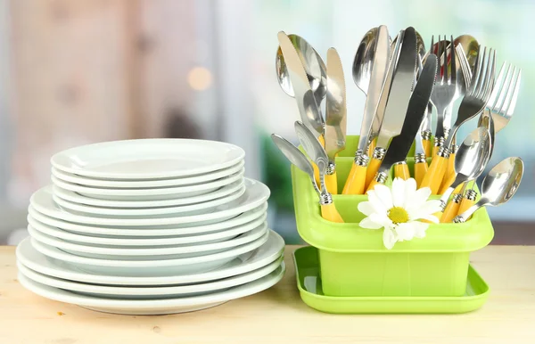 Placas, garfos, facas, colheres e outros utensílios de cozinha sobre fundo brilhante — Fotografia de Stock