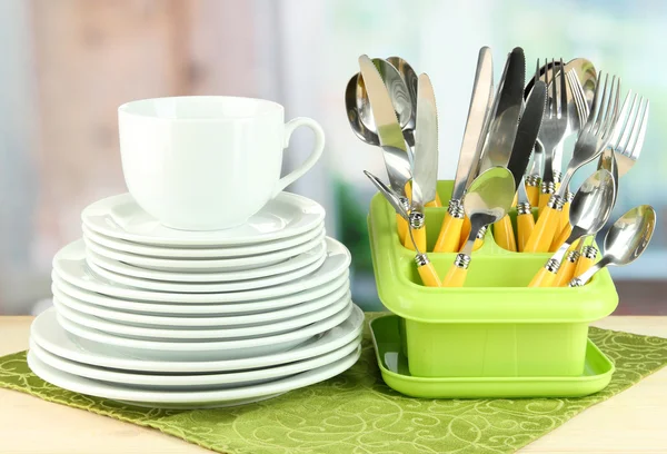 Placas, garfos, facas, colheres e outros utensílios de cozinha em guardanapo de cor, no fundo brilhante — Fotografia de Stock