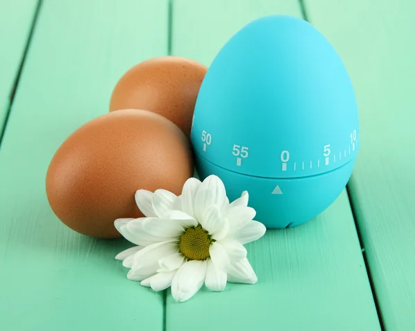 Blaue Eieruhr und Eier, auf farbigem Holzhintergrund — Stockfoto