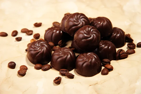 Choklad godis och kaffe bönor, på beige papper bakgrund — Stockfoto