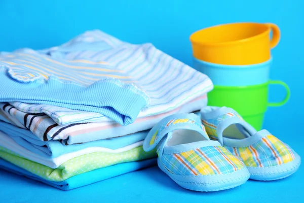 Pile of baby clothes on blue background — Stock Photo, Image