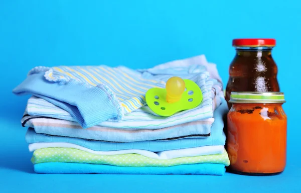 Stapel Babykleidung auf blauem Hintergrund — Stockfoto