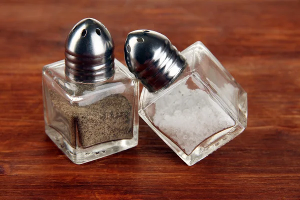 Recipientes de sal e pimenta em mesa de madeira close-up — Fotografia de Stock