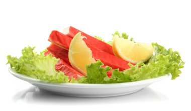 Yengeç sopalarla marul yaprakları ve plaka üzerinde beyaz izole limon