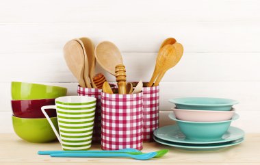 Cups, bowls nd other utensils in metal containers isolated on light background