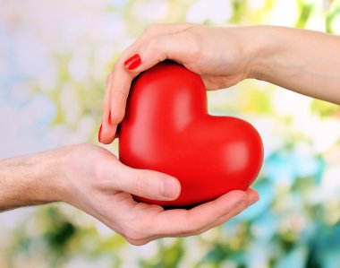 kadın ve adam ellerini, yeşil zemin üzerine kırmızı kalp