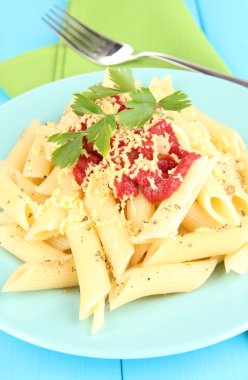 Mavi ahşap masa üstünde domates soslu makarna yemek rigatoni yakın çekim