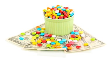 renkli bir kase üzerinde beyaz izole dolarlık banknotlar üzerinde duran şekerler