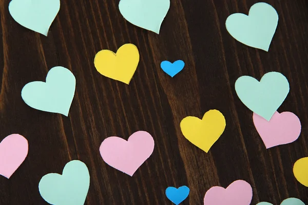 Muchos corazones de papel coloridos en primer plano de mesa de madera — Foto de Stock