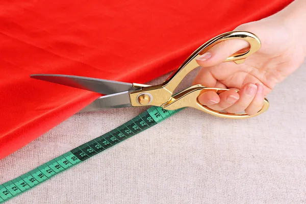 Costurera corte tela roja sobre fondo de tela beige — Foto de Stock