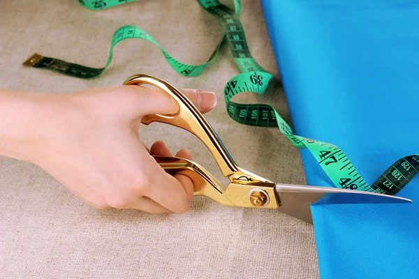 Seamstress corte tecido azul no fundo tecido bege — Fotografia de Stock