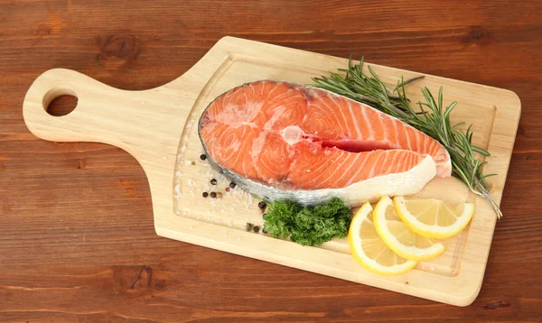 Fresh salmon steak on cutting board, on wooden background — Stock Photo, Image