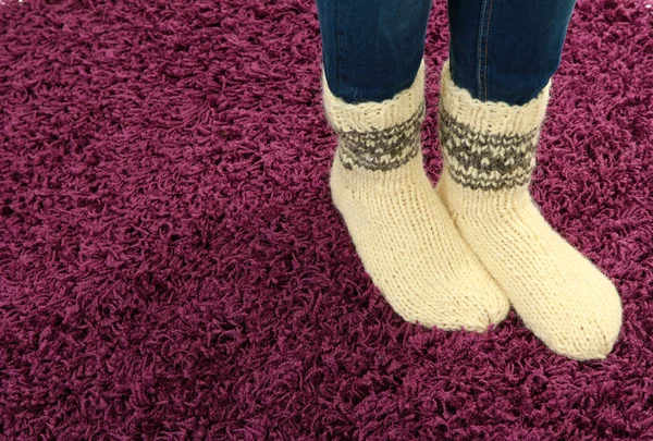 Patas femeninas en calcetines de colores sobre fondo de alfombra de color — Foto de Stock