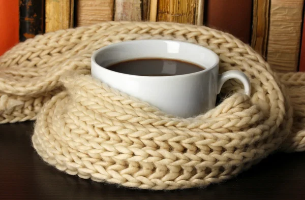 Kopje koffie verpakt in sjaal op boeken achtergrond — Stockfoto