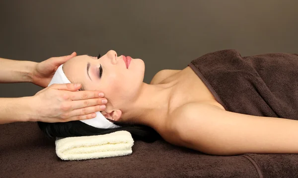 Hermosa joven en el salón de spa tomando masaje en la cabeza, sobre fondo oscuro — Foto de Stock