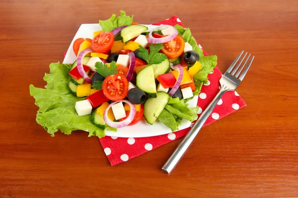 Ízletes görög saláta, fából készült háttér — Stock Fotó