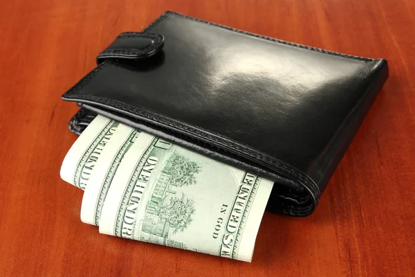 Wallet with hundred dollar banknotes, on wooden background — Stock Photo, Image