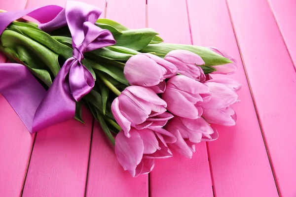 Schöner Strauß lila Tulpen auf rosa Holzgrund — Stockfoto