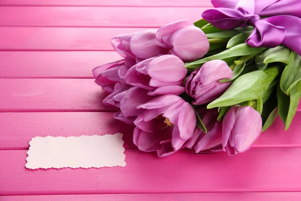 Schöner Strauß lila Tulpen auf rosa Holzgrund — Stockfoto