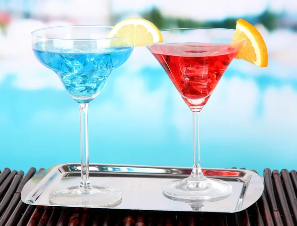 Glasses of cocktails on table near pool — Stock Photo, Image