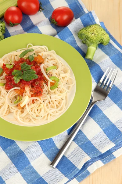 Espaguete saboroso com molho e legumes na placa na mesa de madeira close-up — Fotografia de Stock