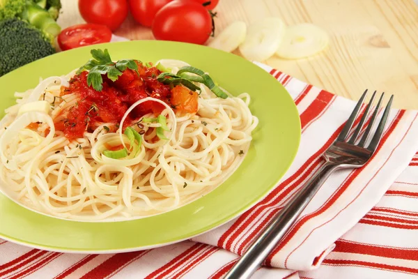 Espaguete saboroso com molho e legumes na placa na mesa de madeira close-up — Fotografia de Stock