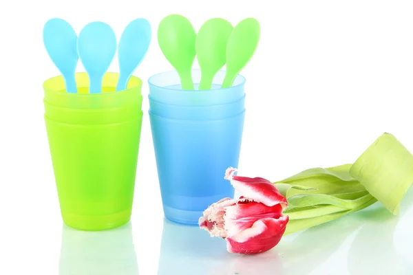 Blauw en groen plastic bekers en lepels, roze tulp geïsoleerd op wit — Stockfoto