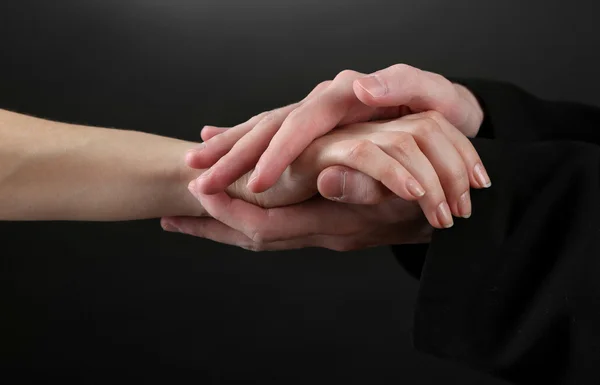 Sacerdote sosteniendo la mano de mujer, sobre fondo negro —  Fotos de Stock