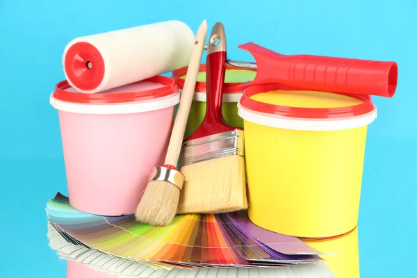 Set for painting: paint pots, brushes, paint-roller, palette of colors on blue background — Stock Photo, Image