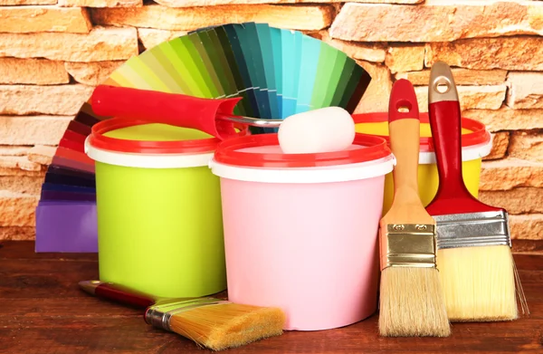 Set for painting: paint pots, brushes, paint-roller, palette of colors on stone wall background — Stock Photo, Image