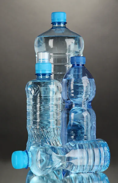 Gri arka plan üzerinde farklı su şişeleri — Stok fotoğraf