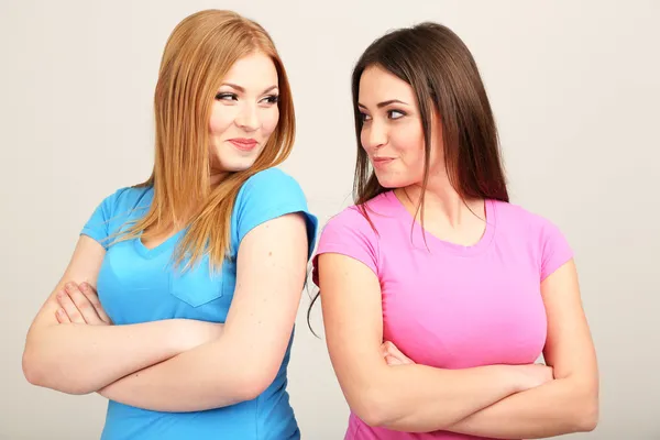 Zwei Freundinnen streiten sich vor grauem Hintergrund — Stockfoto